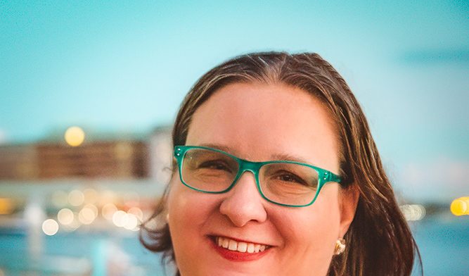 Michele Butcher-Jones standing in front of Tampa Bay wearing a white shirt.