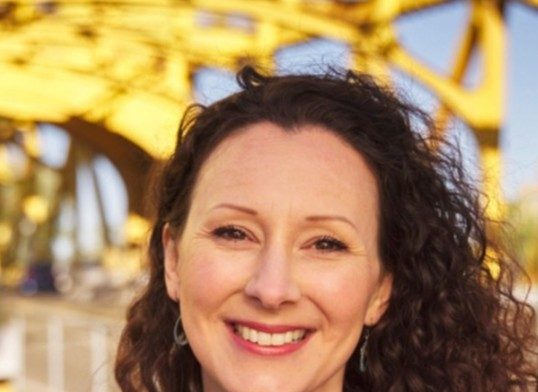 Isla Waite is a white woman with shoulder-length dark hair.