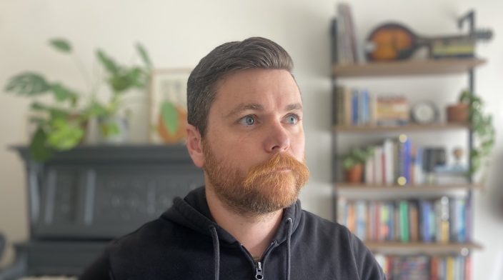 Brian is a white man in his 30s with short brown hair and facial hair