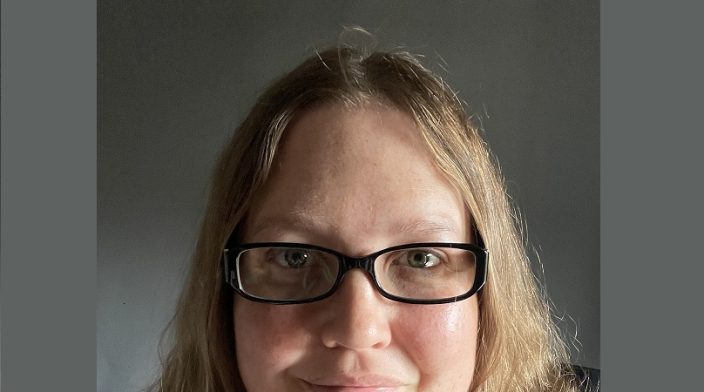 Helen is wearing glasses with her golden hair in a bob, smiling at the camera.