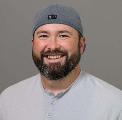 Mark Steadman is a white male in his 30's with medium thick beard, and a white sox cap on backwards.
