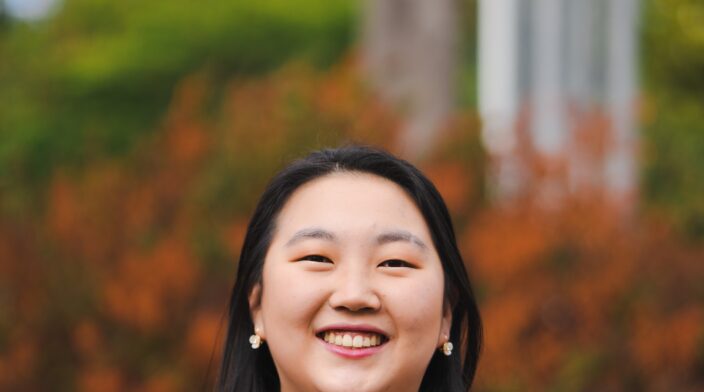 Grace is a Korean woman in her 20's with long black hair and a big friendly smile.