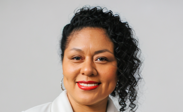 Jacquelyn Lopez is a hispanic woman with a joyful smile and long curly hair.