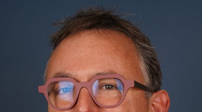A Caucasian man with slightly greying hair and wearing glasses