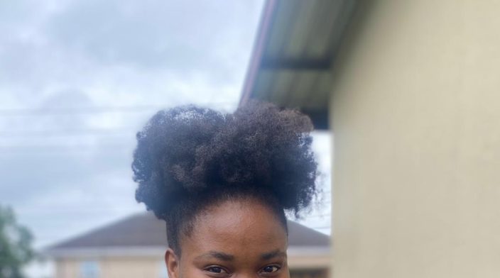 Victoria Nduka is a black woman in her 20's with thick afro hair packed in a high puff and a big friendly smile.