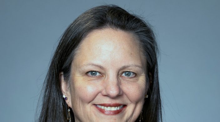 Studio portrait of Jessica, caucasian woman in her 50s with long brown hair.