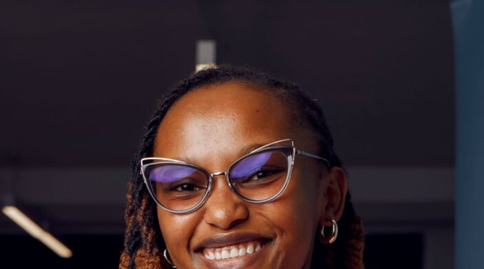 Rose is a Black African woman with dark skin, wearing glasses and braids, and often seen with a warm, welcoming smile