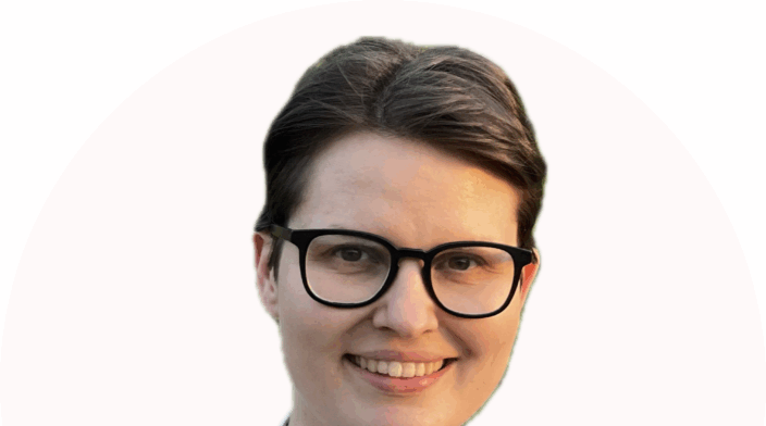 Olivia is a white woman with short brown hair, big dark glasses, wearing a blue and white striped blouse, smiling into the camera.