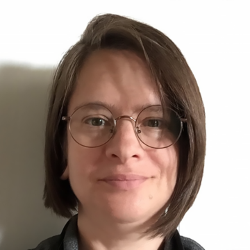 Diana is a white woman with brown hair in a bob. She has hazel eyes behind her eyeglasses and a calm, confident hint of a smile.